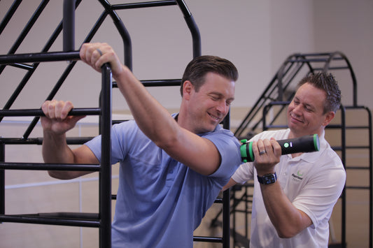 A therapist work with a client in a stretch cage and applying Rapid Release® vibration therapy to help with muscular pain, stretching and more.